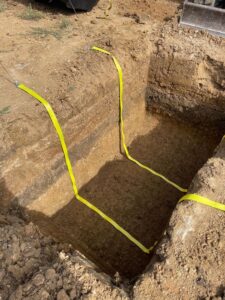 Fosse d'excavation profonde avec sangles de levage jaunes pour l'installation d'une structure sur un chantier.