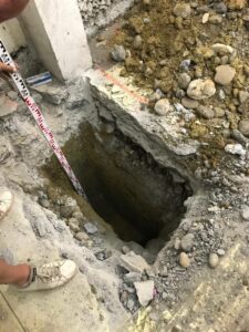 Mesure de la profondeur d'une excavation avec une mire graduée à côté d'une fondation en béton.