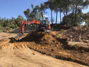 Pelleteuse Doosan orange en action sur un chantier de terrassement, creusant un tas de terre sous un ciel dégagé.